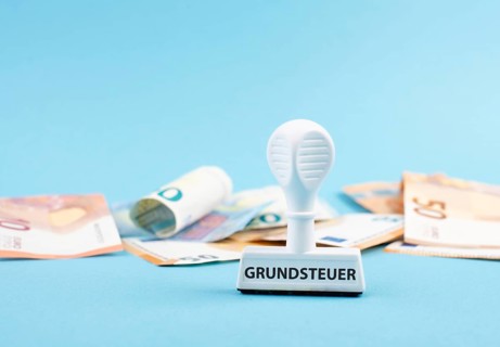 Euro banknotes and a stamp with the german word forr property tax, new law in Germany on houses