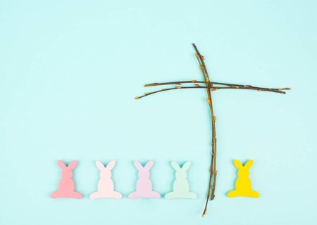 Easter bunny or rabbit with a religious cross made from willow branches, christian spring holiday,
