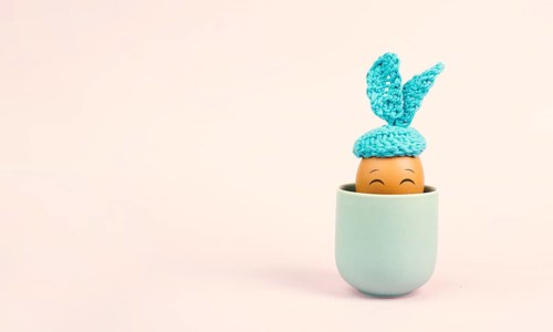 Cute easter bunny or rabbit with a smiling egg face in a cup, spring holiday, greeting card
