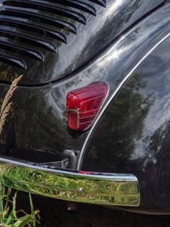 Detailed view of a black vintage car, showing the rear light and reflective chrome parts in