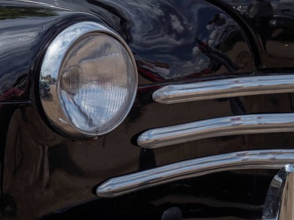 Detailed view of a black vintage car, showing the front headlight and chrome trim, winterswijk,