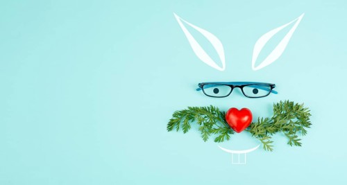 Easter rabbit face with a heart shaped nose, whiskers from carrot leaves and eyeglasse, holiday