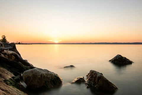 Sunset on the shore of a lake in summer. Colourful sky with a wide view of the horizon. Natural