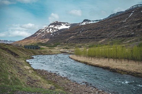 Idyllic river at Seydisfjordur, Iceland, with mountain range in the background, wide angle shot,