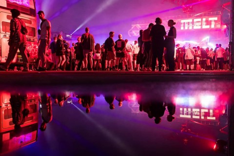 Festival visitors are reflected in a puddle at the Melt Festival in Ferropolis on 12 July 2024.