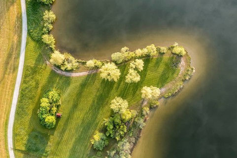 Aerial view of bathing area on small peninsula at lake Rottachsee with little hut, clouds are