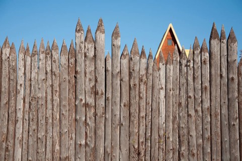 The wooden fence of sharpened logs timber