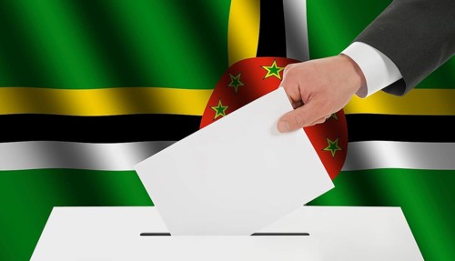 The Dominica flag and the hand with the bulletin about the ballot box