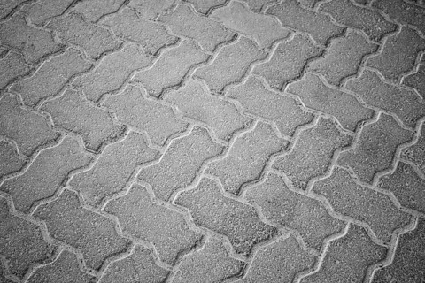 An interlocking pattern of grey paving stones forming a textured brickwork pavement, Concrete floor
