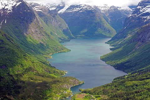 Impressive lake framed by high mountains and dense forests under a cloudy sky, Lovatnet, Loen,