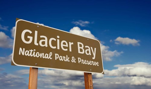 Glacier bay national park and preserve (alaska) road sign against blue sky and clouds