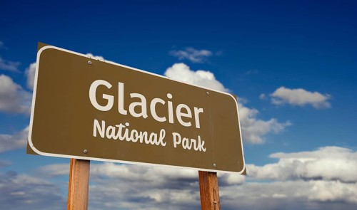 Glacier national park (montana) road sign against blue sky and clouds