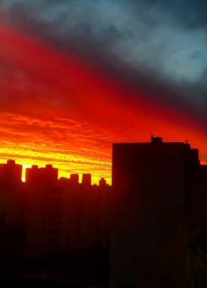 Fiery sunset casting silhouettes of buildings against a dramatic orange and dark sky.Belarus, Minsk