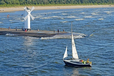 Sailboat passing the lighthouse when entering the port of Swinoujscie, Swinemünde, West Pomerania,