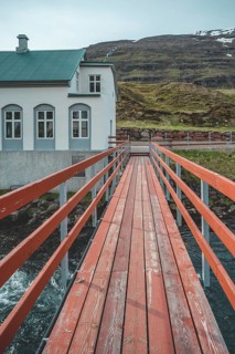 Red wooden Bridge over a river near Seydisfjordur, Iceland, vertical shot, Europe