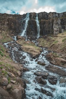 Idyllic waterfall Budareyrarfoss with river at Seydisfjordur, Iceland, vertical shot, Europe