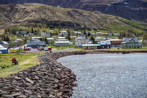 Residential area with residential buildings and houses behind a lake in front of a mountain in