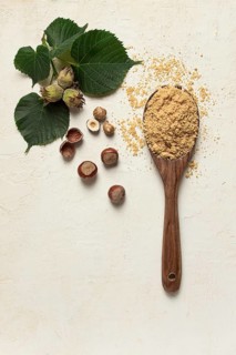 Wooden spoon with hazelnut flour, top view, no people, on a white table