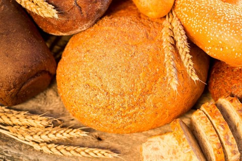 Homemade bread and wheat on the wooden table in autumn field