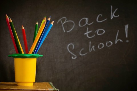 Coloured pencil in holder against blackboard with text