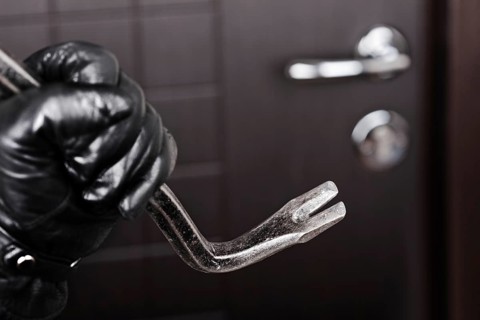Crime scene, criminal thief or burglar hand in gloves holding metal crowbar break opening home door