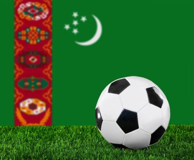 The Turkmen flag and soccer ball on the green grass