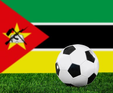 The Mozambique flag and soccer ball on the green grass