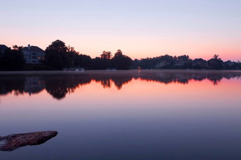 Lake landscape with houses. Misty sunrise