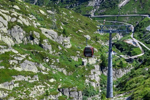 Cabin of cable car Hospizbahn passes cable car mast over gorge mountainous alpine terrain to