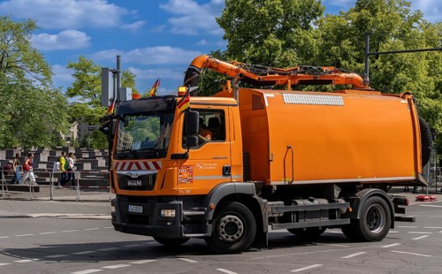 Operational vehicle of the Berlin city cleaning service with German flags on the driver's cab,