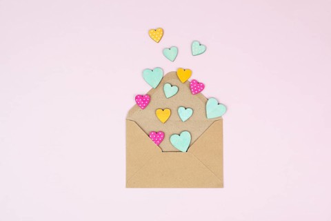 Valentine day greeting card, envelope with hearts on pastel background, love symbol, flat lay