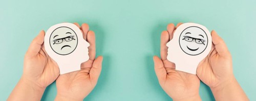Holding a head with a sad and a happy face in the hands, mental health concept, positive and