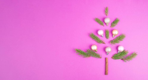 Christmas tree made from fir branches, pink baubles and a cinnamon stick as the trunk, greeting