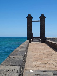 A stone footbridge leads to a Tor tor with a view of the blue sea and sky, arrecife, Lanzarote,