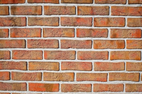 Weathered red brick wall with visible grout lines arranged in a horizontal pattern, background