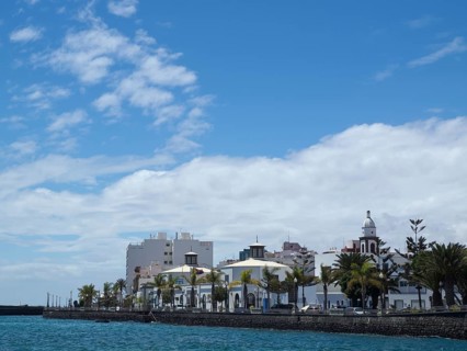 City view with a row of buildings and palm trees along the sea shore under a blue sky, arrecife,