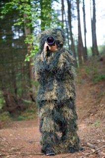 Photographer wearing camouflage clothing in the forest, wildlife animal photography with a camera
