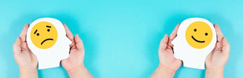 Holding a head with a sad and a happy face in the hands, mental health concept, positive and