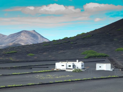 A white house on black ground with mountains and blue sky in the background, arrecife, Lanzarote,