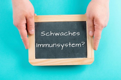 Weak immune system is standing in german language on a chalkboard, healthy eating and lifestyle