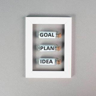Three glass bottles with the words idea, plan and goal in a frame, education, marketing and