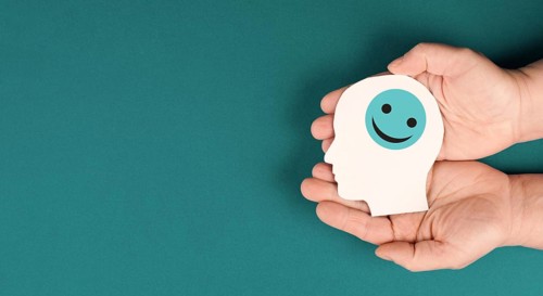 Holding a head with a smiling face in the hands, mental health concept, positive mindset, support
