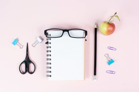 Empty notebook with a pen, eyeglasses and an apple on a pastel colored desk, brainstorming for new