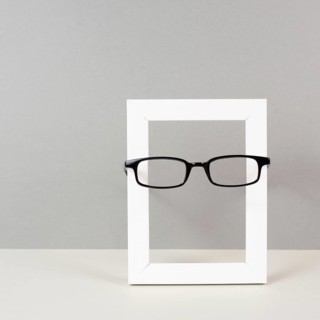 Home interior poster mock up with wooden frame and eyeglasses, gray wall background, copy space for