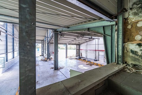 Large interior of a commercial hall with lots of light and a metal structure, demolition site,