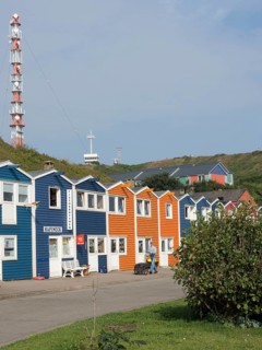 Colourful houses next to a large lighthouse on a quiet street, Heligoland, North Sea, Germany,