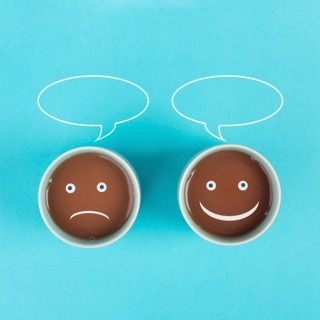 Cup of coffee with a sad and a happy face, positive and negative mindset, support and evaluation