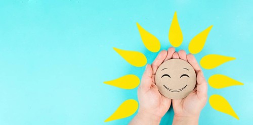 Holding a smiling face with yellow petals in the hands, mental health concept, positive mindset,