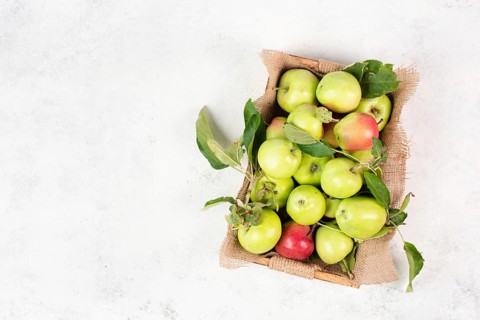 Basket with fresh ripe apples standing on a table, fruit harvest in the summer, healthy organic