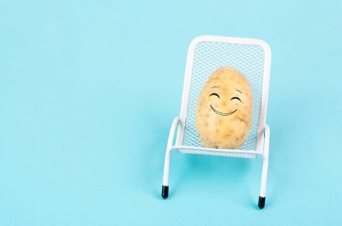 Potato with a funny face is sitting in lounge chairs, happy holiday, greeting card